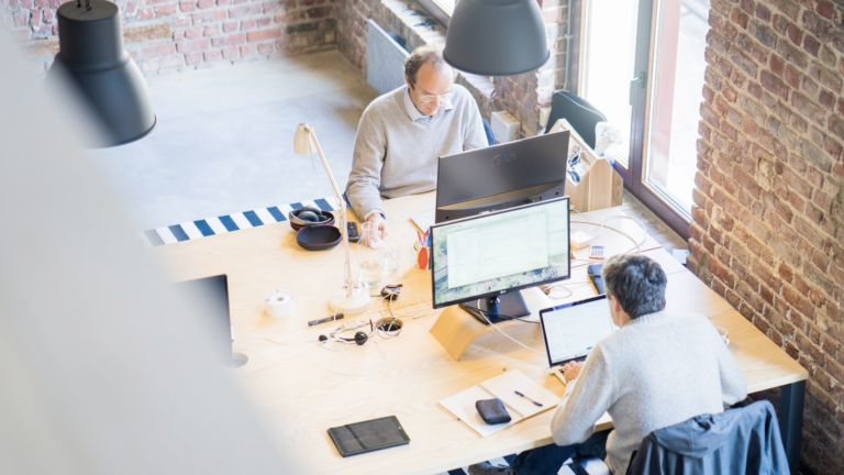 Photo of two people working at their desks