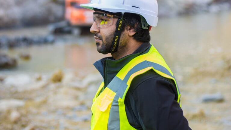 Photo of a man wearing high visibility vest, safety goggles and hard hat